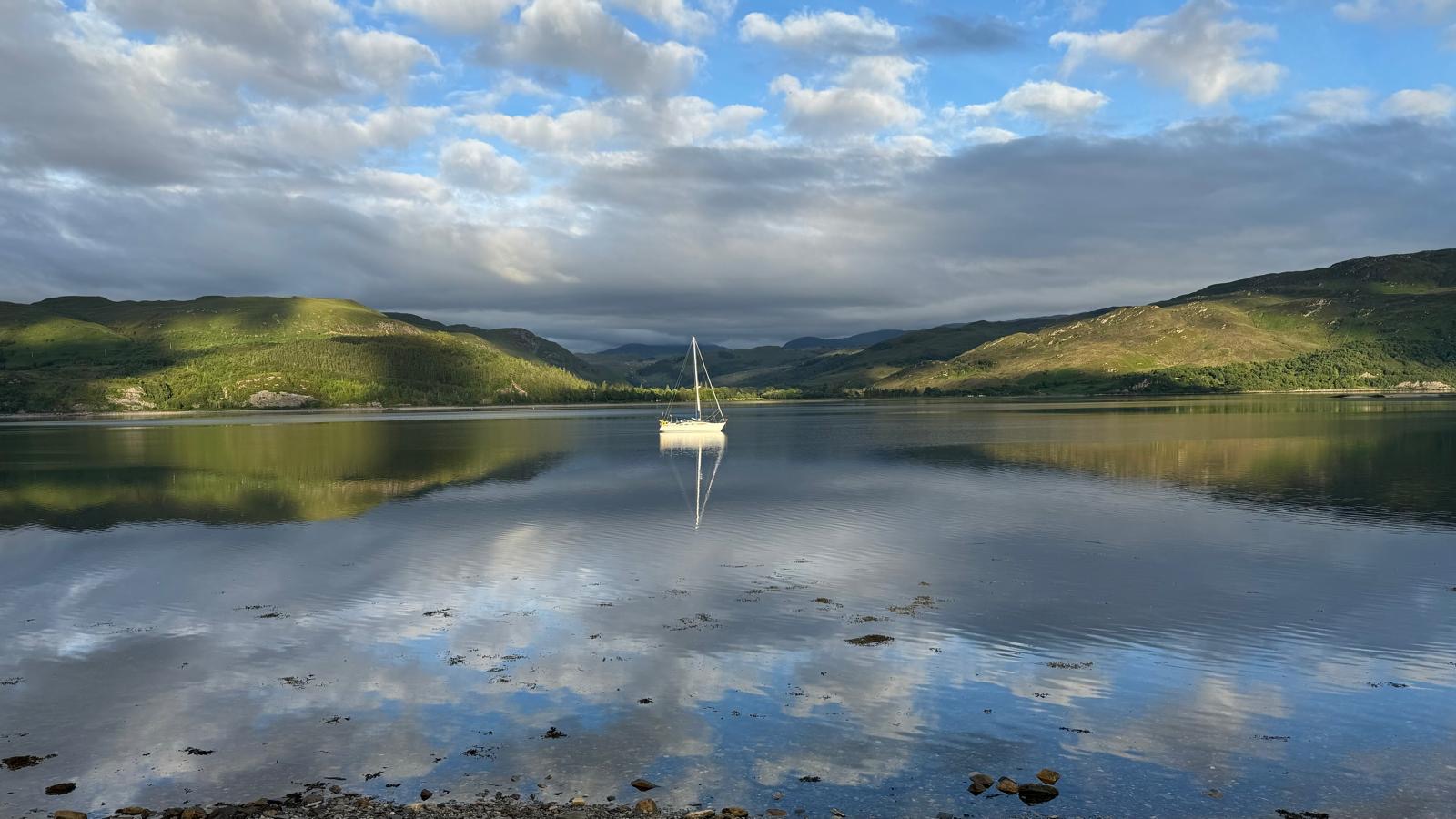 Sailing boat reflected on a calm Loch Carron